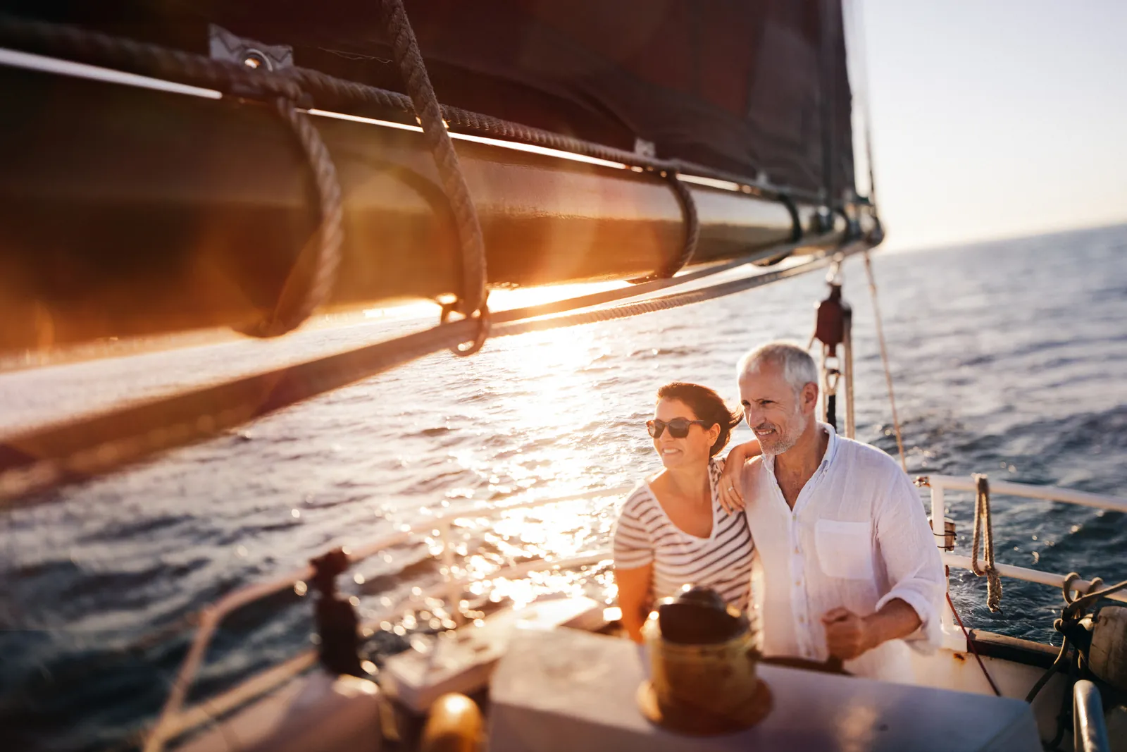 Two members in the cockpit of a yacht at sunset, drinks in hand