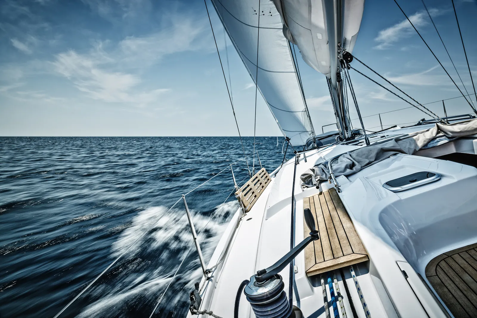 The helm and cockpit of a yacht under way, wake streaming behind
