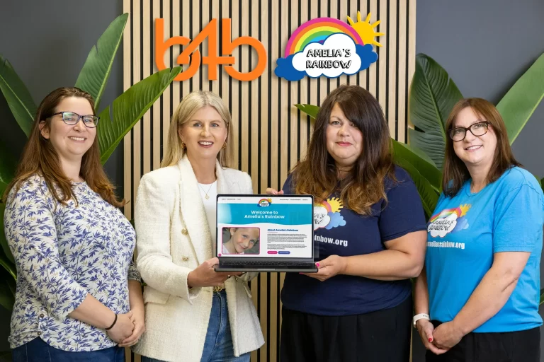 B4B Marketing and Amelia/s Rainbow Charity holding a laptop showing the new web site design