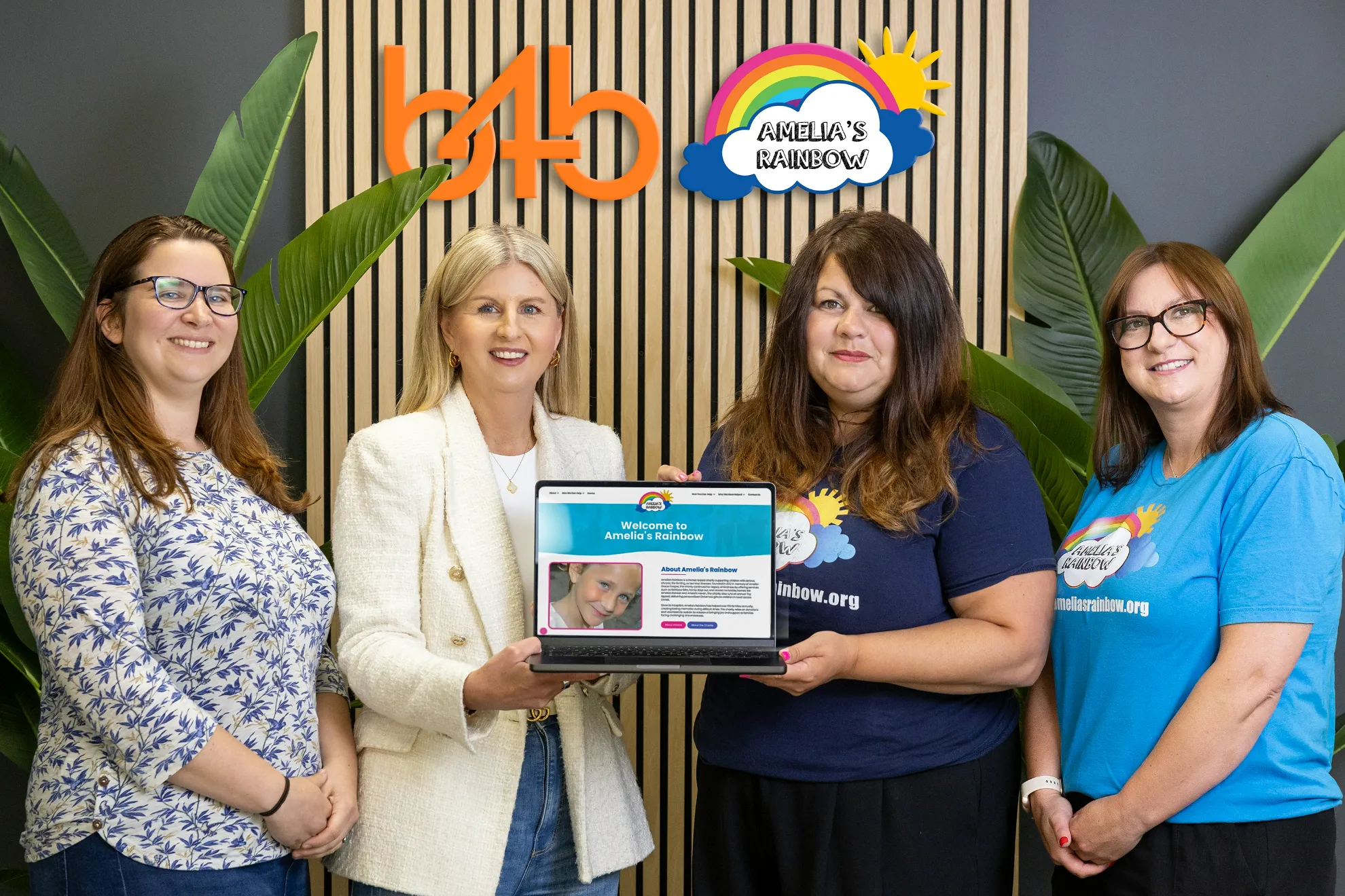 B4B Marketing and Amelia/s Rainbow Charity holding a laptop showing the new web site design