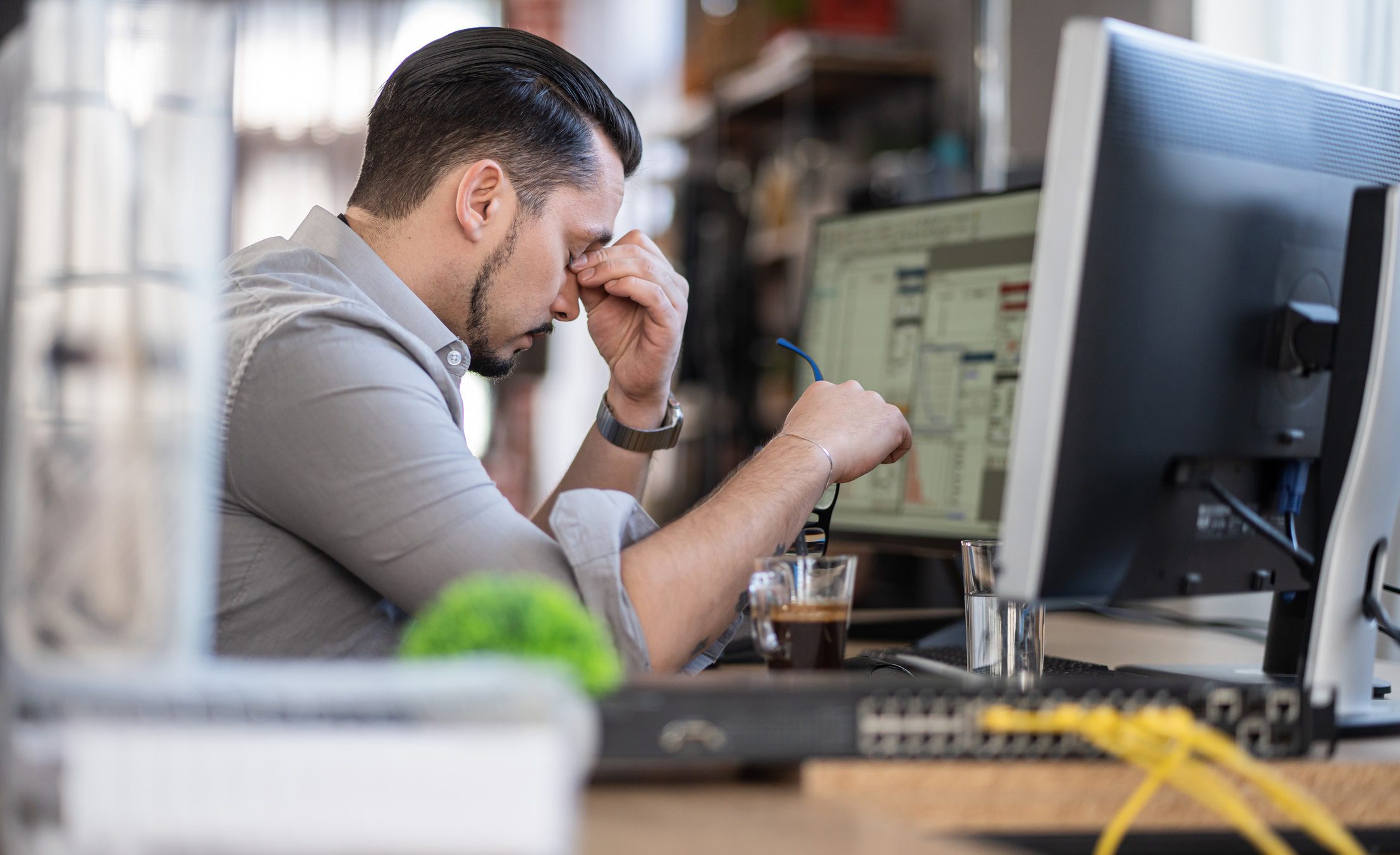 stressed office worker at desk facing computer
