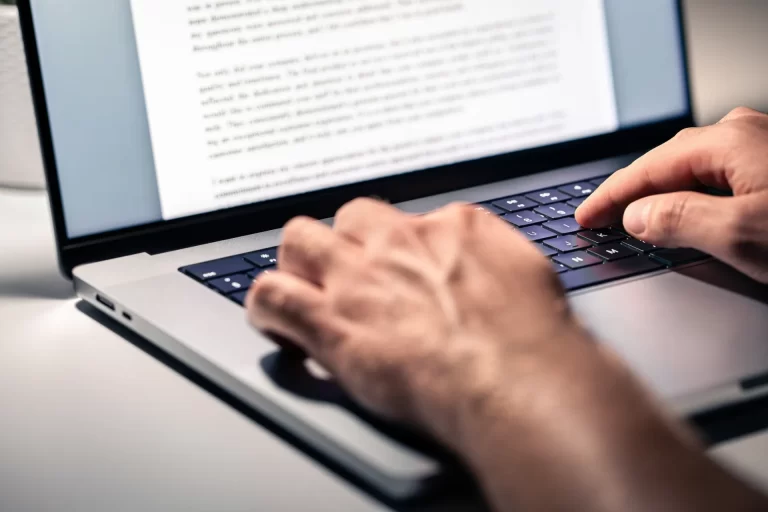 A person is typing on a laptop, focused on updating SEO content for better rankings and improved search engine visibility.
